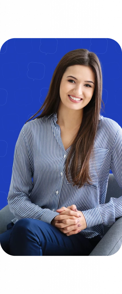 Femme souriante portant une chemise rayée, assise sur un canapé gris, avec un fond bleu.